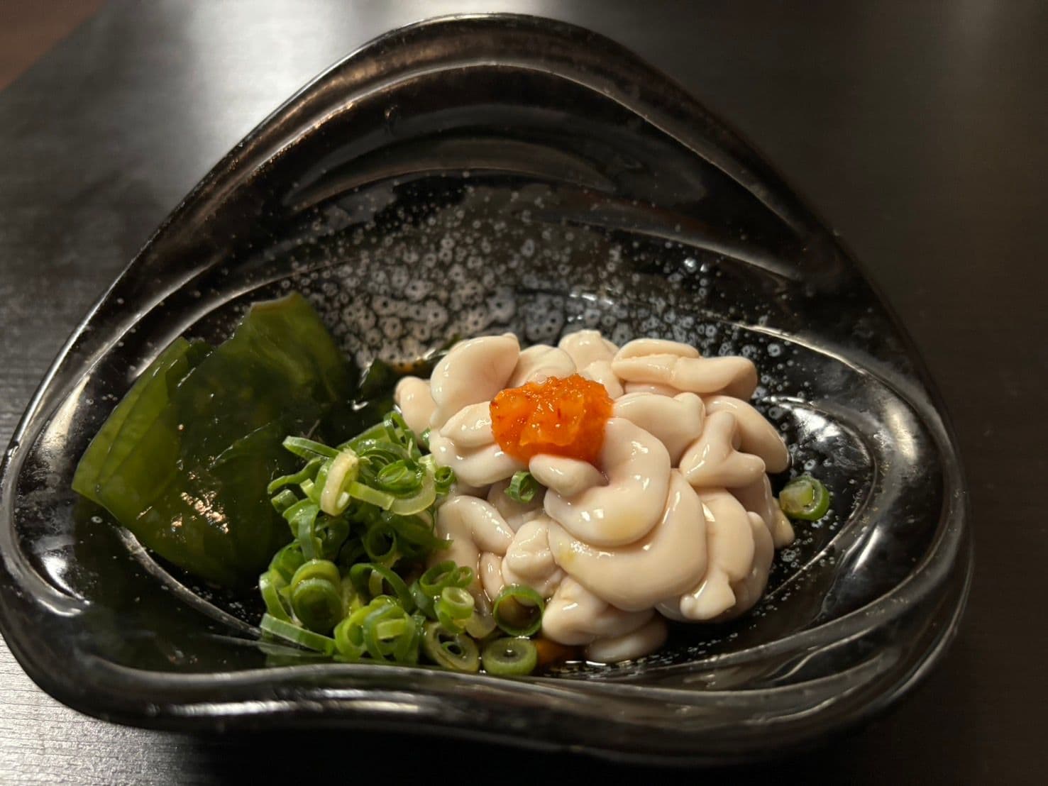 黒い器に盛った白子ポン酢。もみじおろしとわかめ、刻み葱を添えて