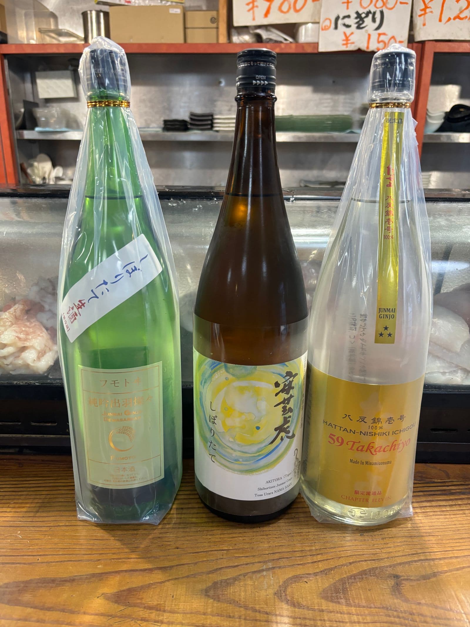 カウンターのネタケース前に並べた日本酒の一升瓶三本